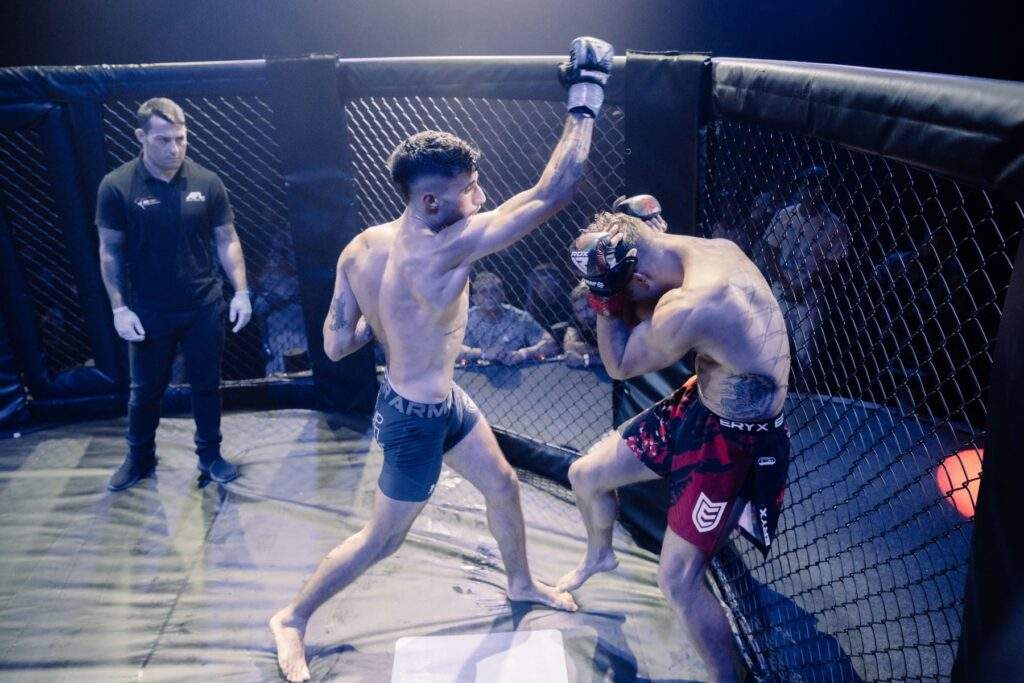 Two MMA fighters grappling against the cage during a Fight Island Championship match in Mallorca